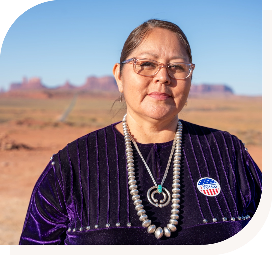 Woman wearing "I Voted" sticker, desert background.